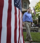 Sean Barney ’98 in a blue shirt and khaki pants walking near an American flag